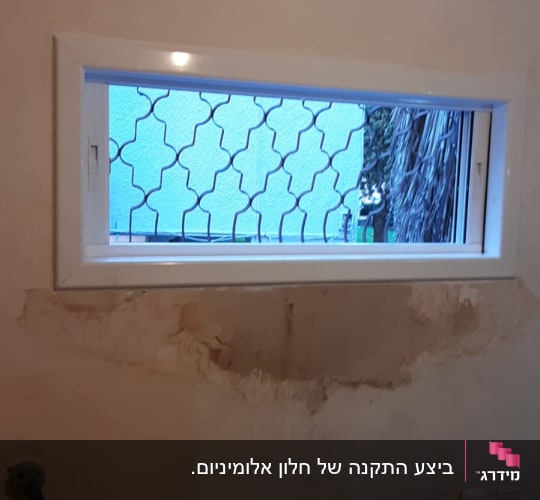 חלון עם מסגרת אלומיניום וקיר מתקלף